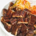 Grilled Pork Belly on a plate with pickled vegetables and spicy vinegar dipping sauce.