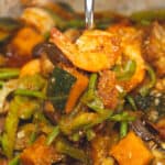 Pinakbet braised in mixed vegetables scooped by a spoon.