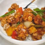 Sweet Sour Chicken topped on rice in a bowl.