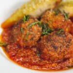 Meatballs with marinara sauce and garlic bread on a plate.
