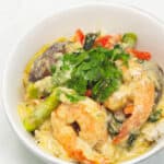 Thai green curry with shrimp topped on rice in a bowl.