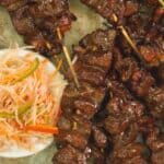 barbecue pork skewers on a plate served with java rice and achara