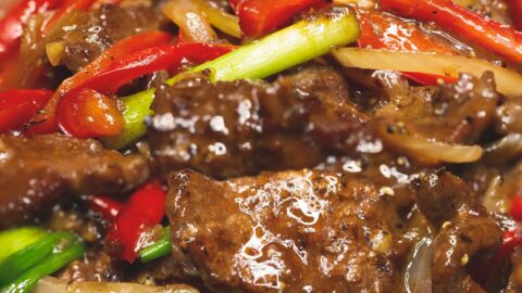 Beef stir fry with onions and peppers in a wok zoomed in.