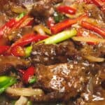 Beef stir fry with onions and peppers in a wok zoomed in.