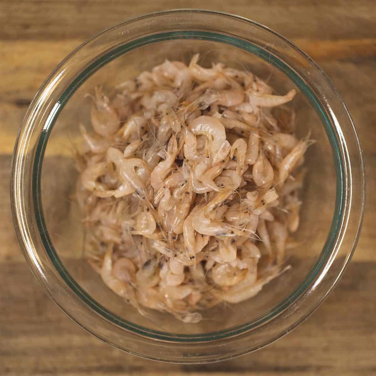 Thawed and rinsed tiny shrimp in a clear bowl. 