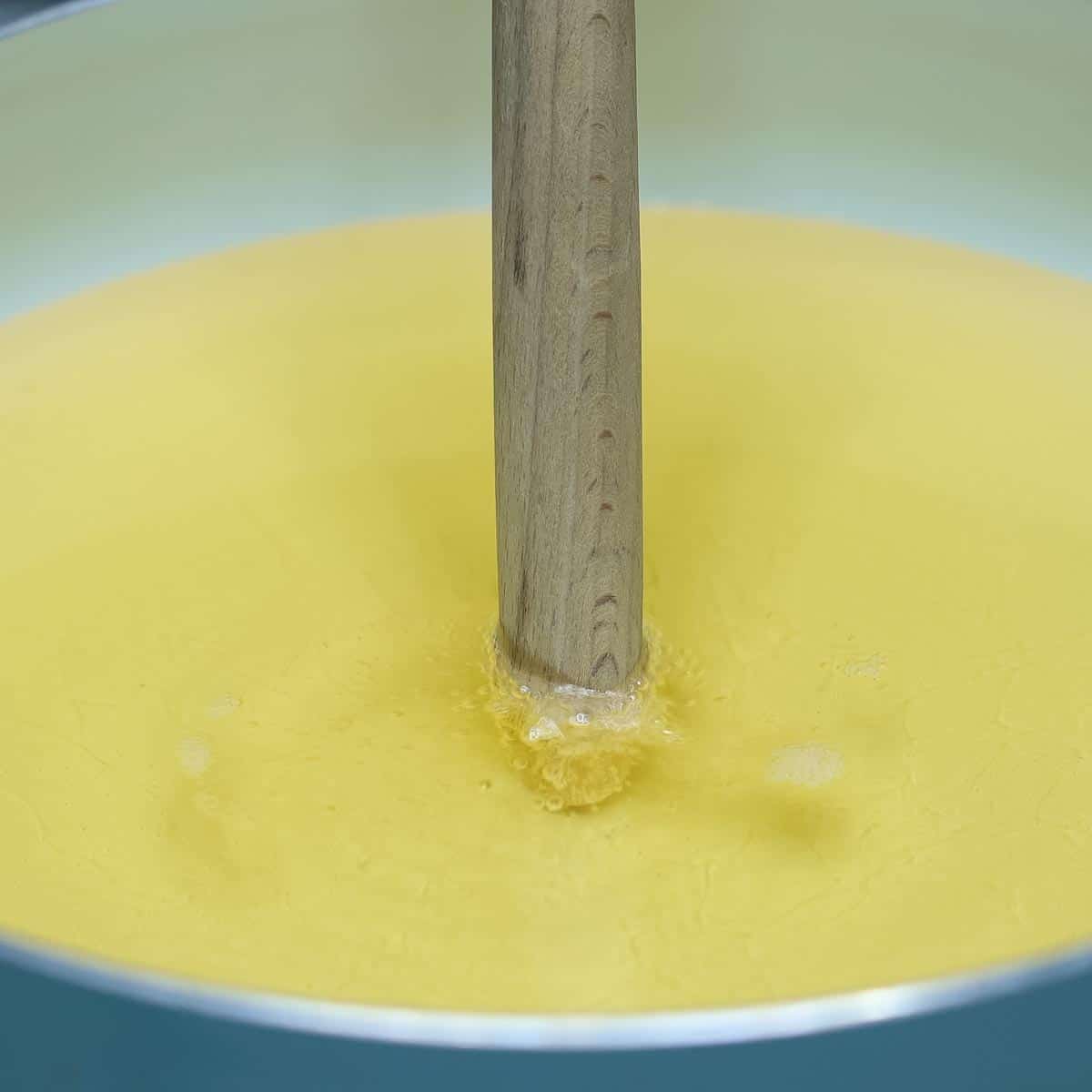 A wooden spoon handle dipped in hot oil with bubbles around it. 