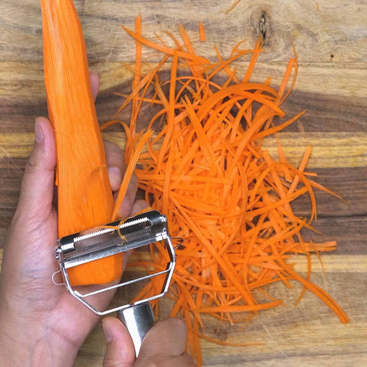 Making thin strips of carrots using a julienne peeler.