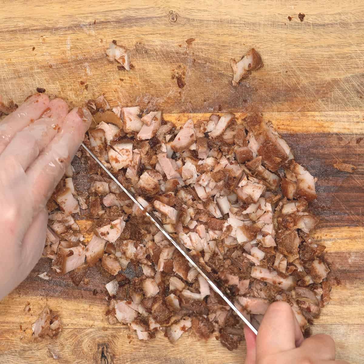 Chopping adobo meat on the cutting board.