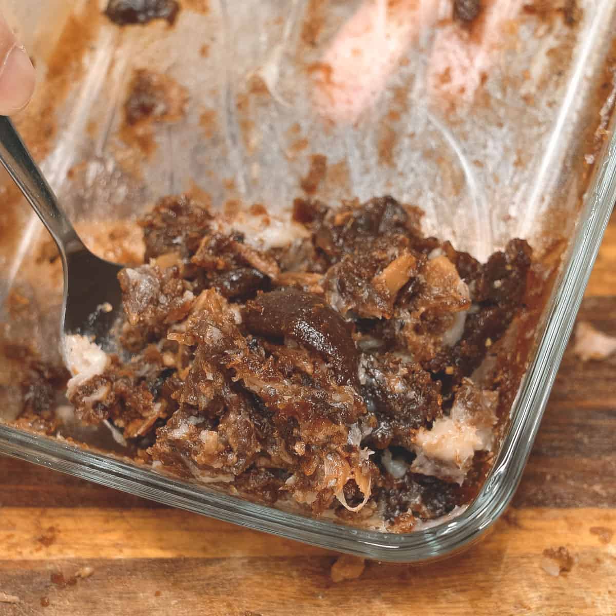 Scraping the solidified adobo sauce in a glass container.