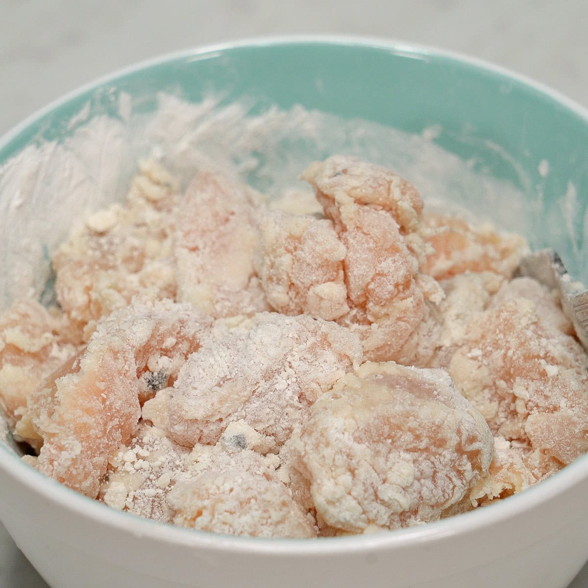 Coated pieces of chicken in the bowl.
