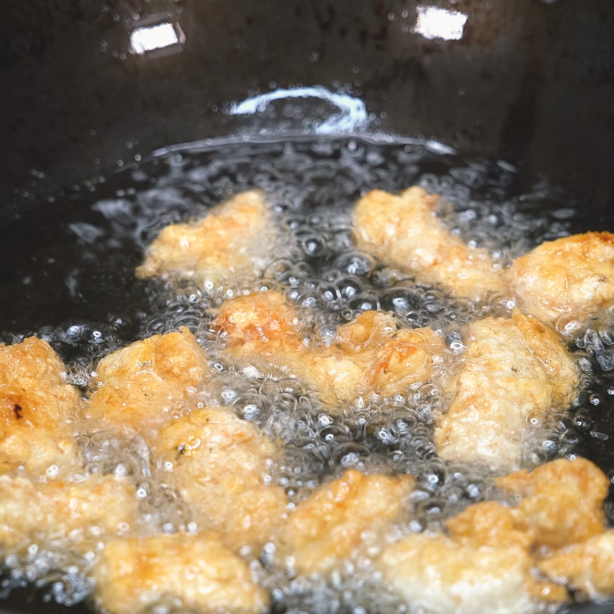 Frying chicken nuggets in hot oil in the wok.