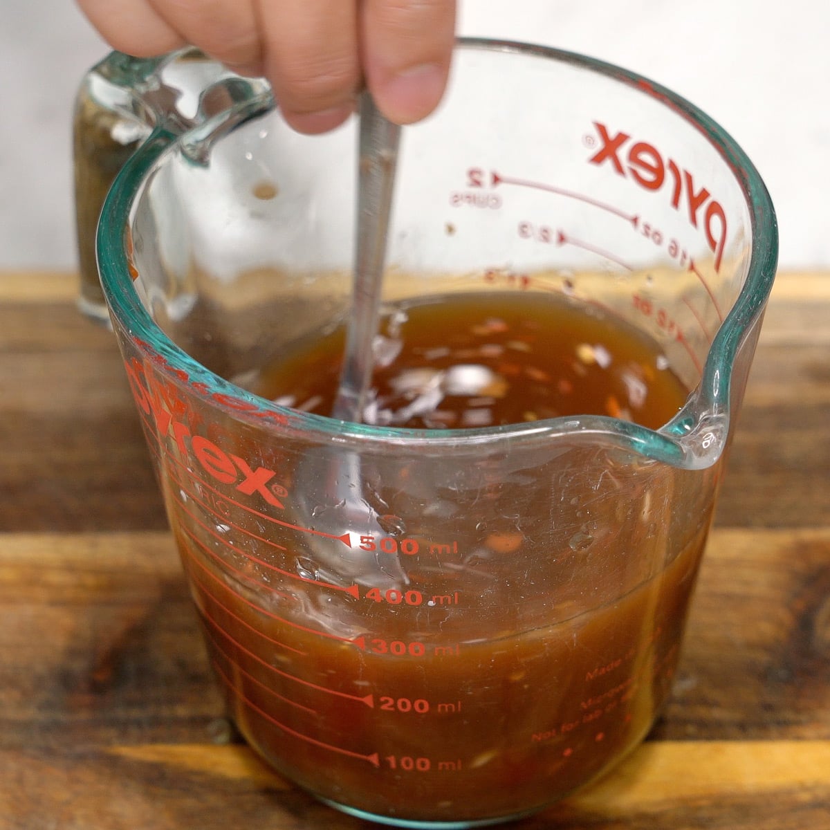 Stirring the sweet and sour sauce in a measuring cup.