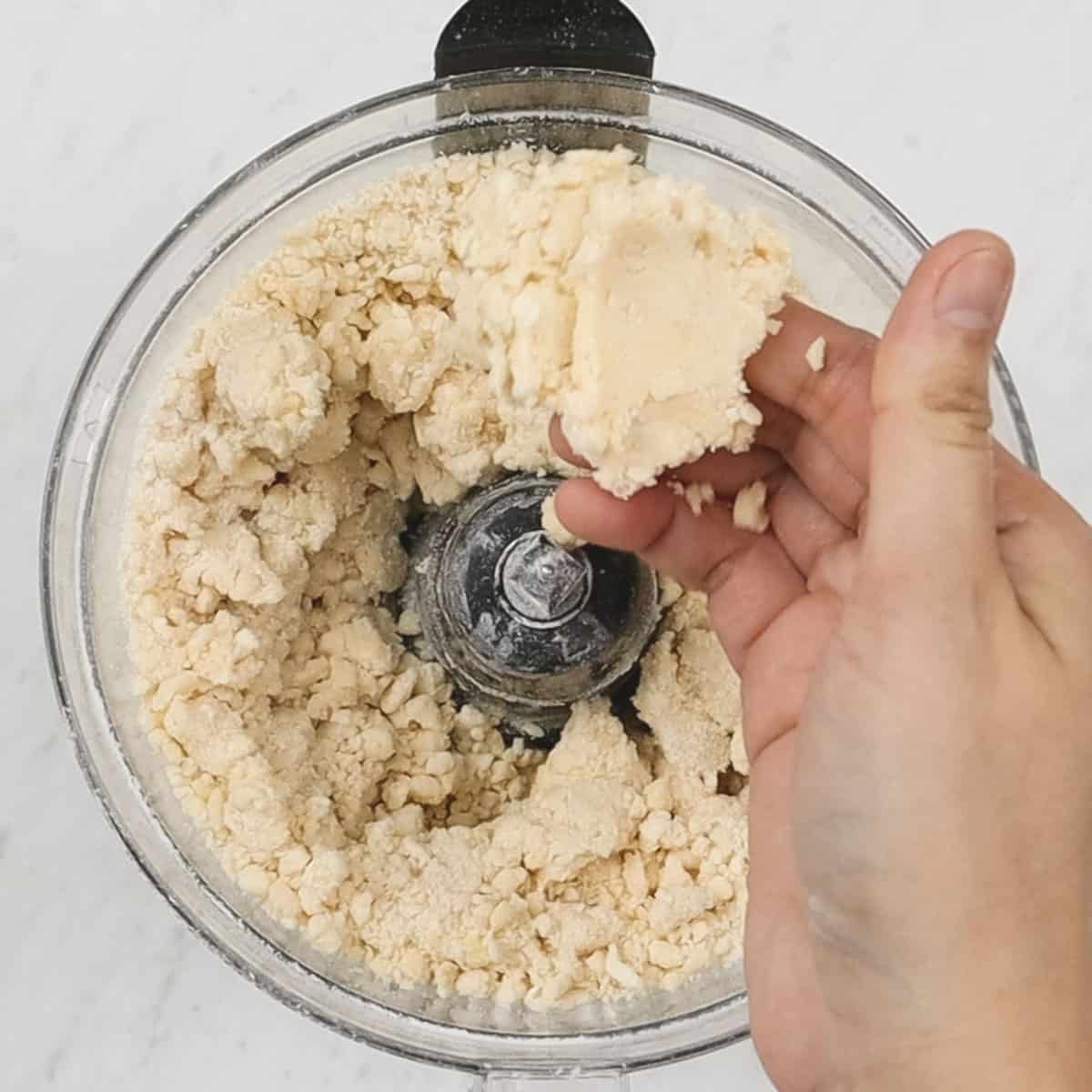Pinching a small piece of shortcrust pastry to check for consistency.