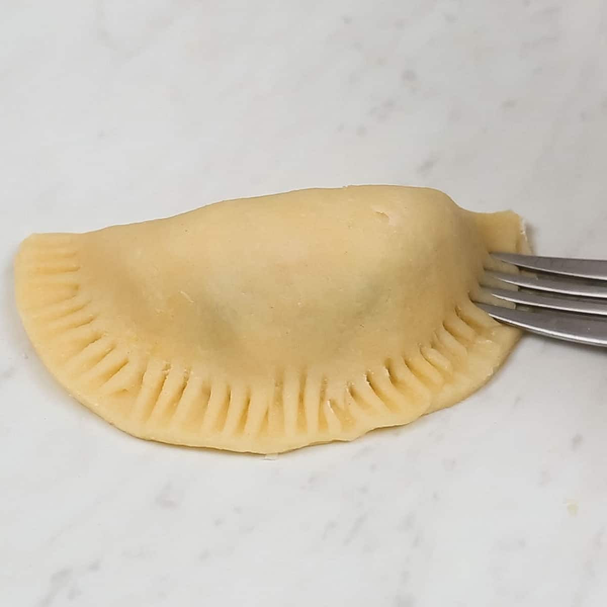 Crimping the edges of a chicken empanada.