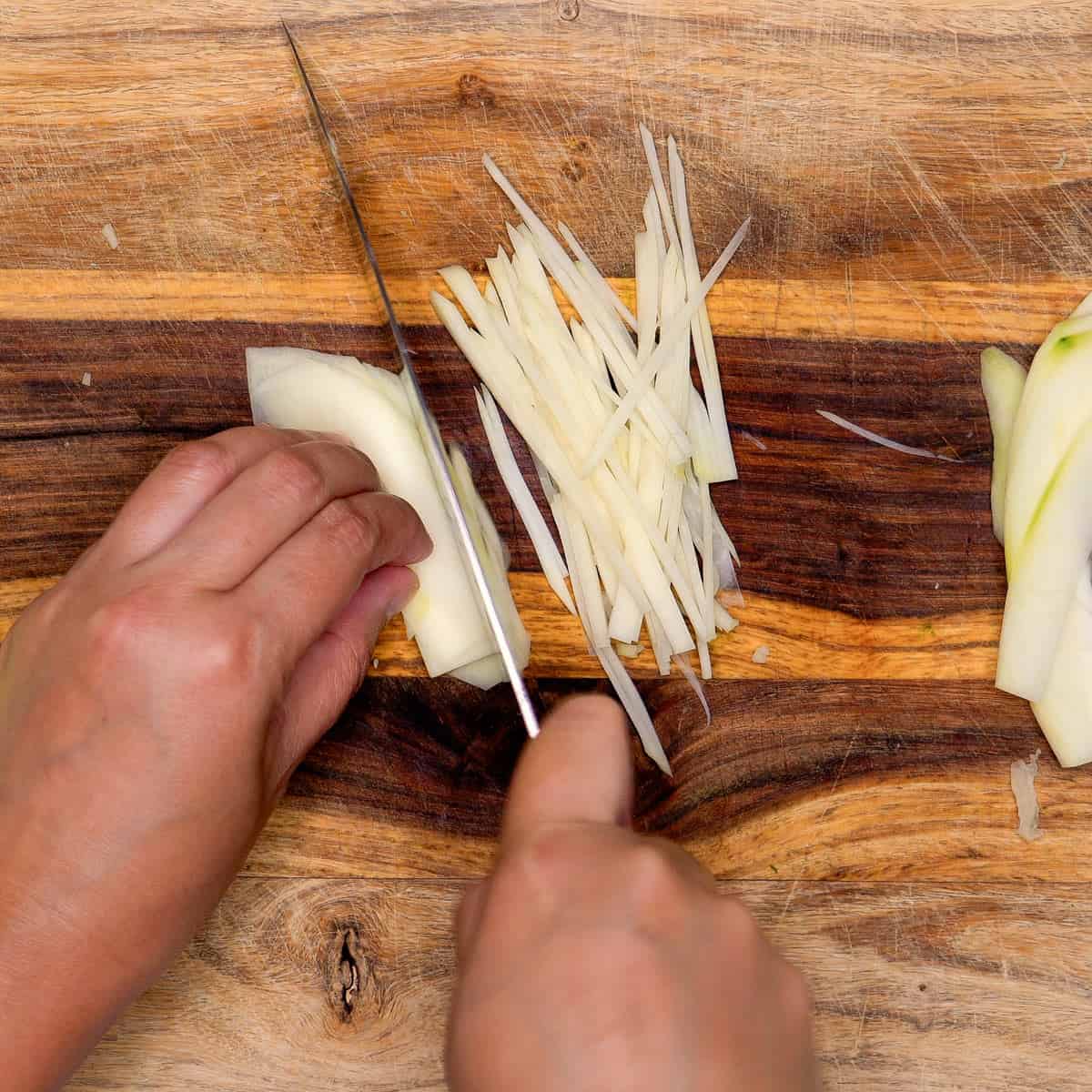 Slicing green papaya thinly into matchsticks.