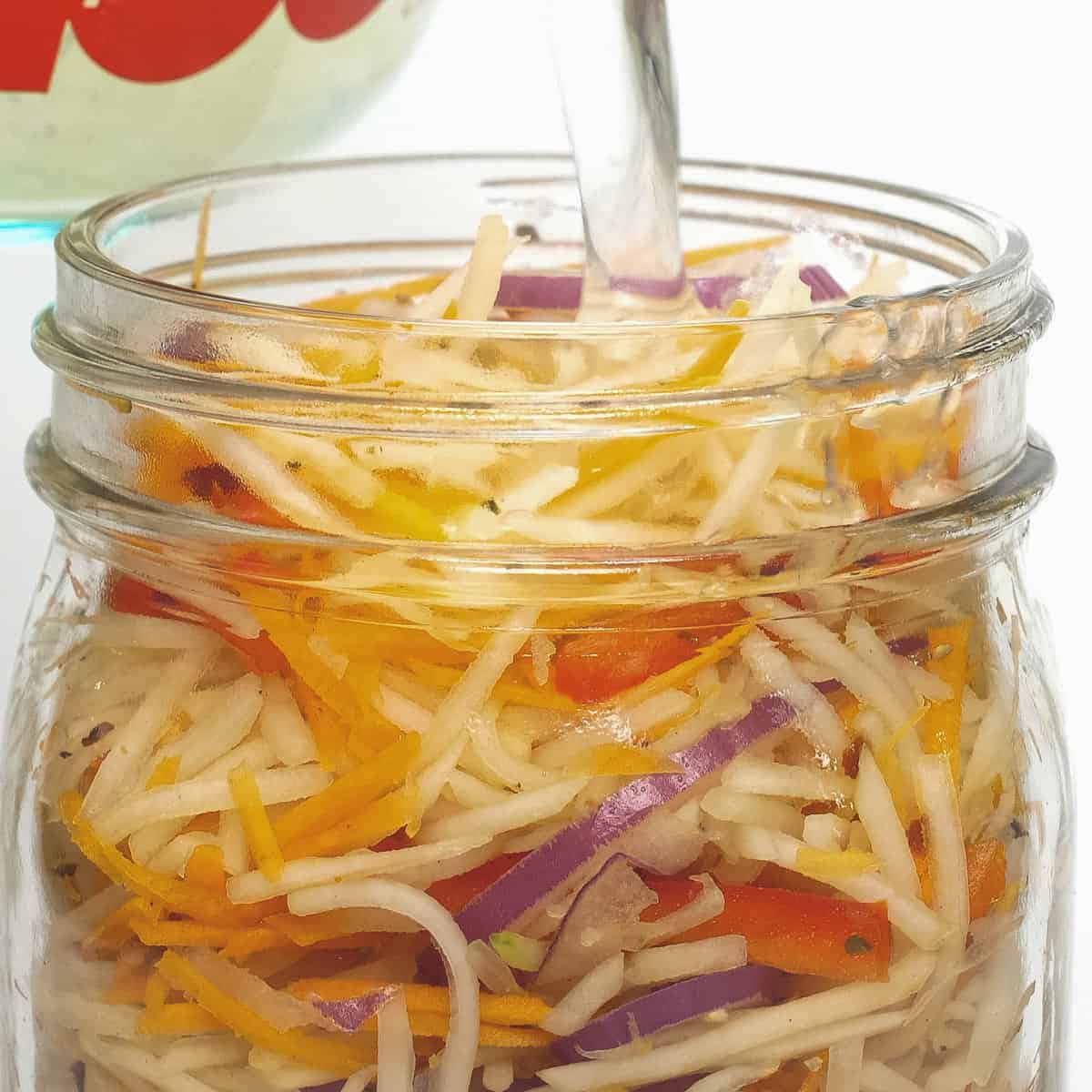 Pouring the brine over the vegetables in the jar.