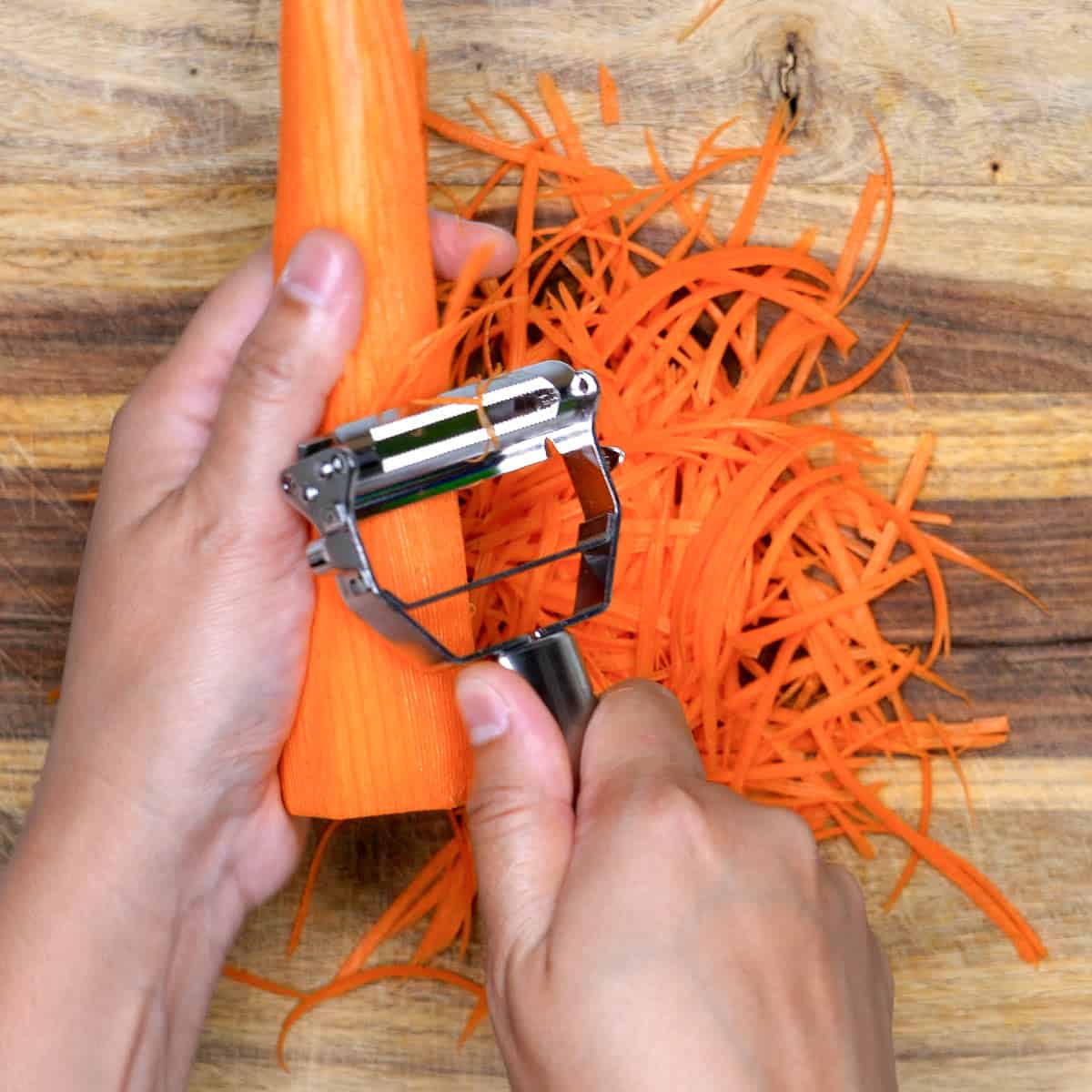 Shredding carrot using a julienne peeler.