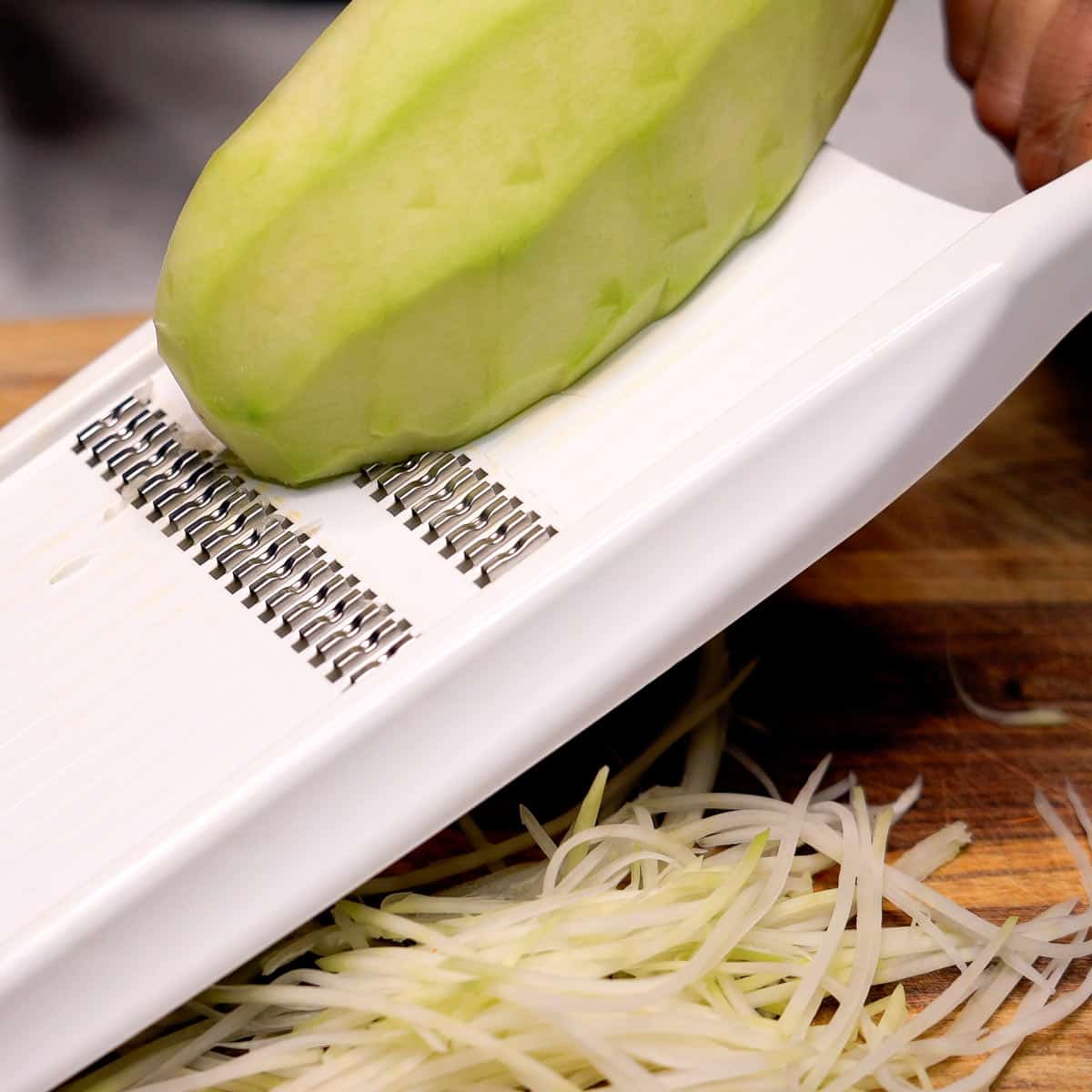 Shredding green papaya using a julienne slicer.
