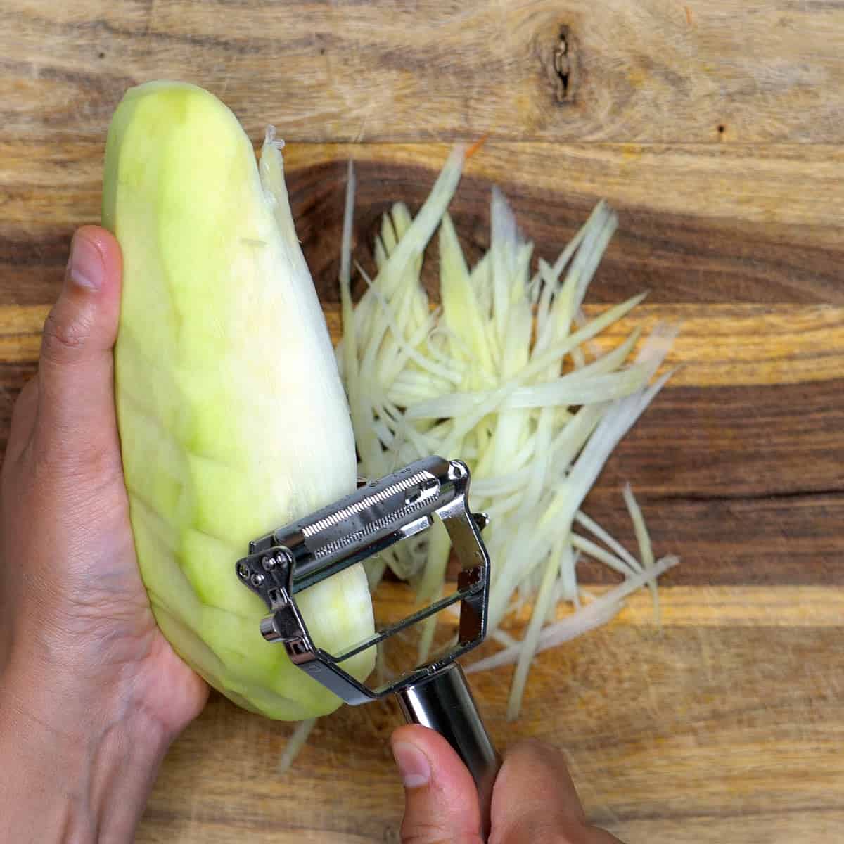 Shredding green papaya using a julienne peeler.