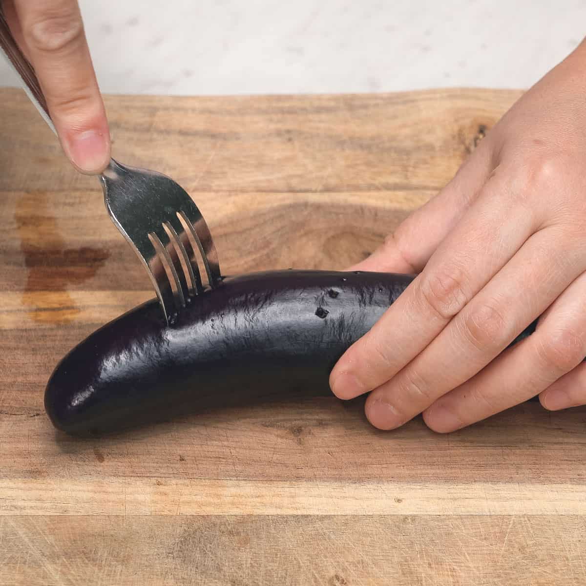 Poking holes in the eggplant with a fork.