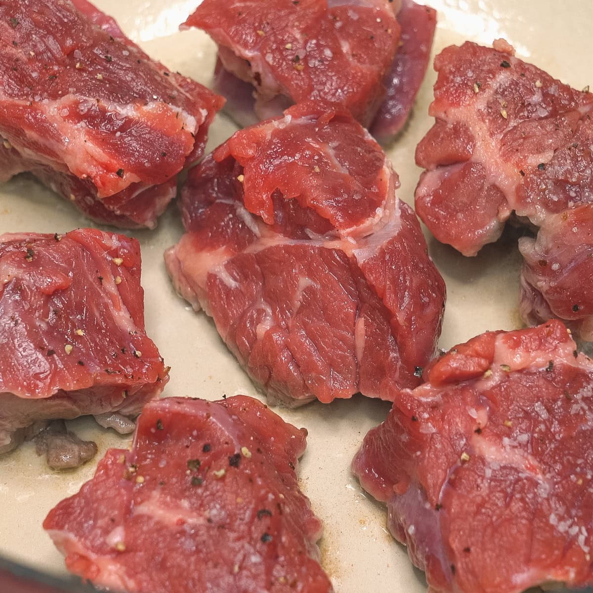 Searing the seasoned beef cubes.