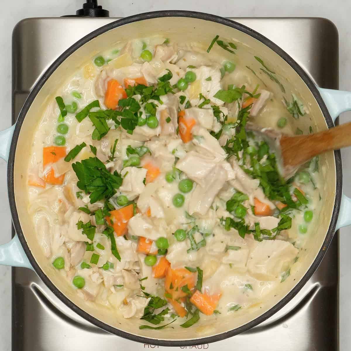 Mixing the chicken pot pie filling in the pot.