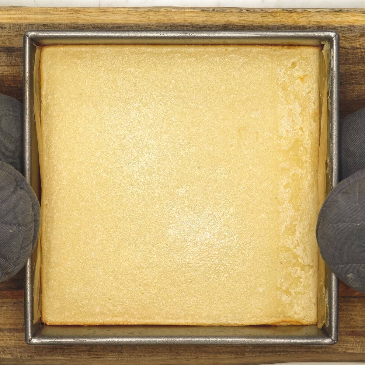 Holding the partially baked cassava cake in the pan. 