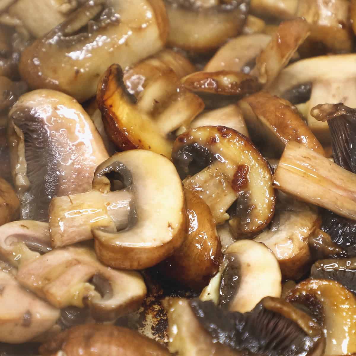 Mixing the browned mushrooms in the pan using a spatula.