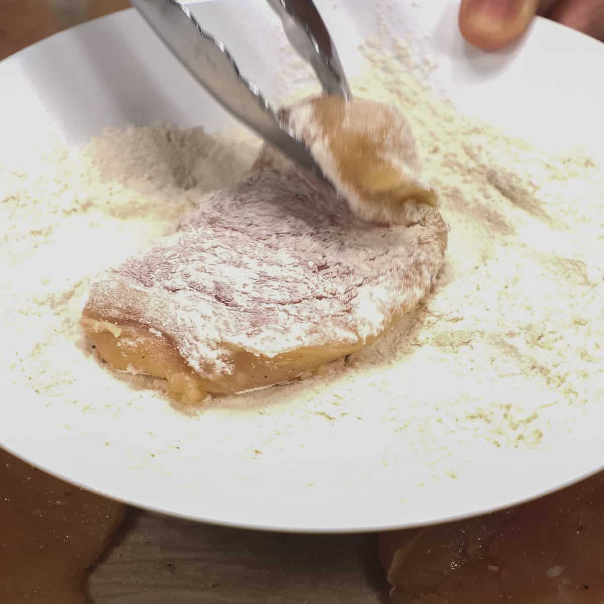 Dredging a chicken cutlet in flour.