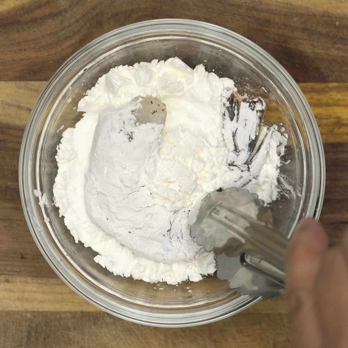 Shrimp dipped in a bowl of cornstarch.