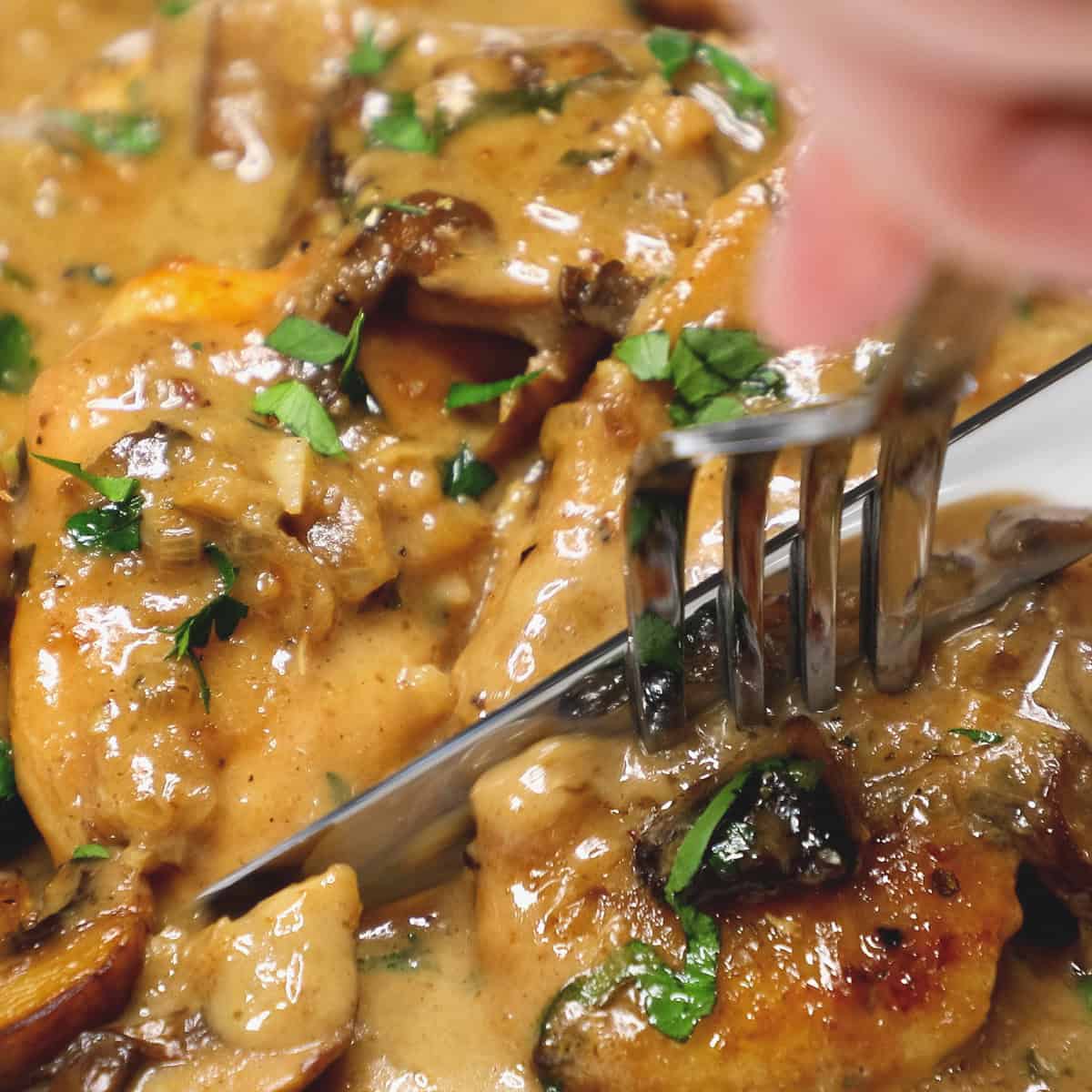 Cutting a small piece of chicken on the plate.