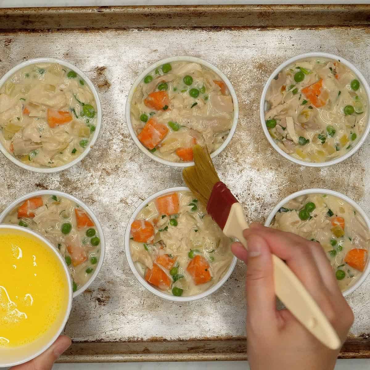 Brushing the sides of the ramekins with egg wash.