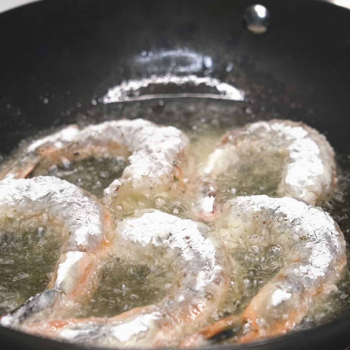 Shallow-frying pieces of shrimp in oil.