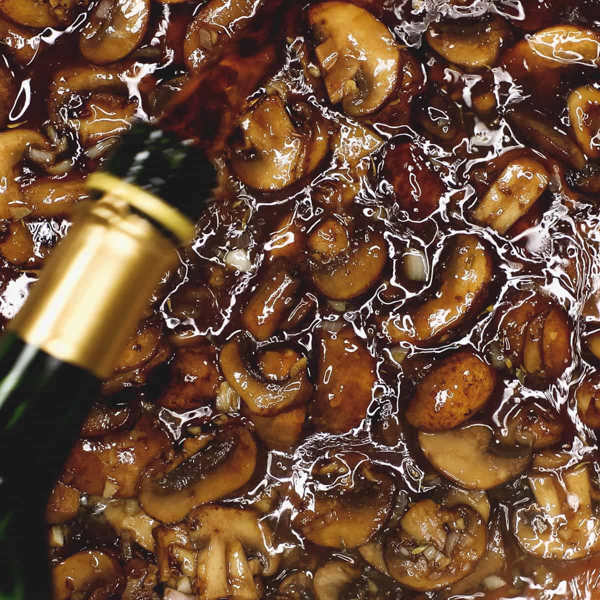 Pouring Marsala wine to the mushrooms in the pan.