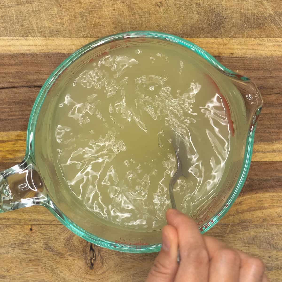 Stirring the chicken stock in the cup.