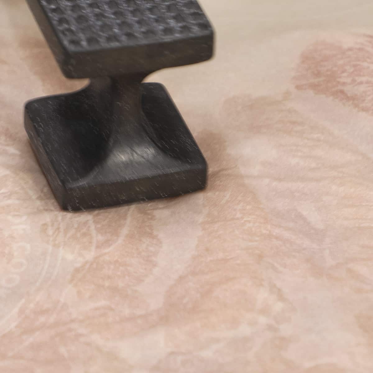 Pounding chicken cutlets placed in between sheets of parchment paper using a meat mallet.