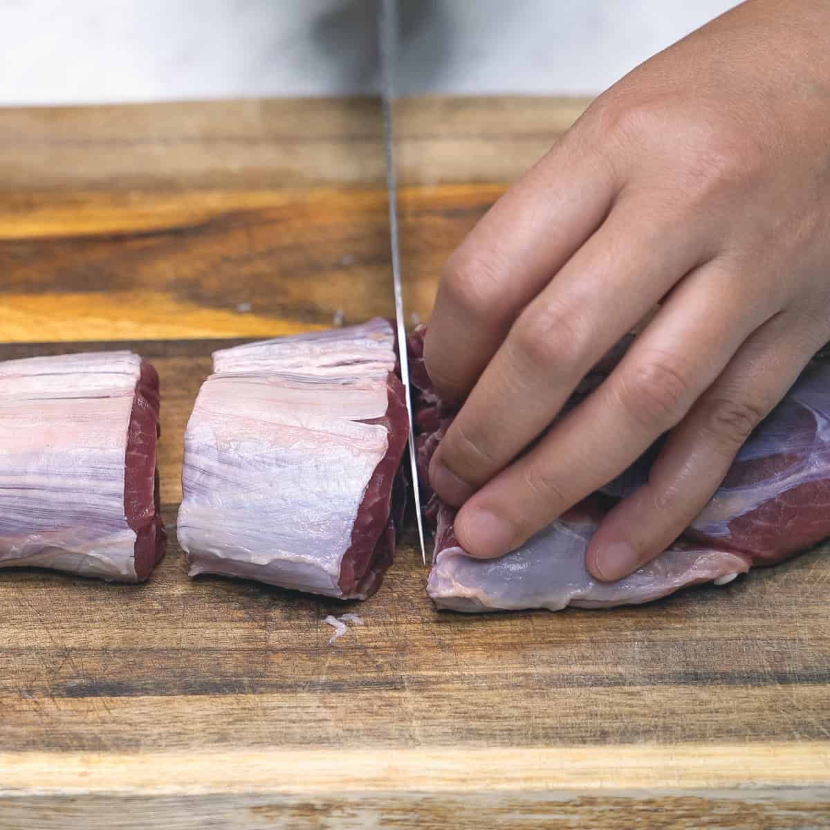 Cutting the meat into sections on a cutting board.