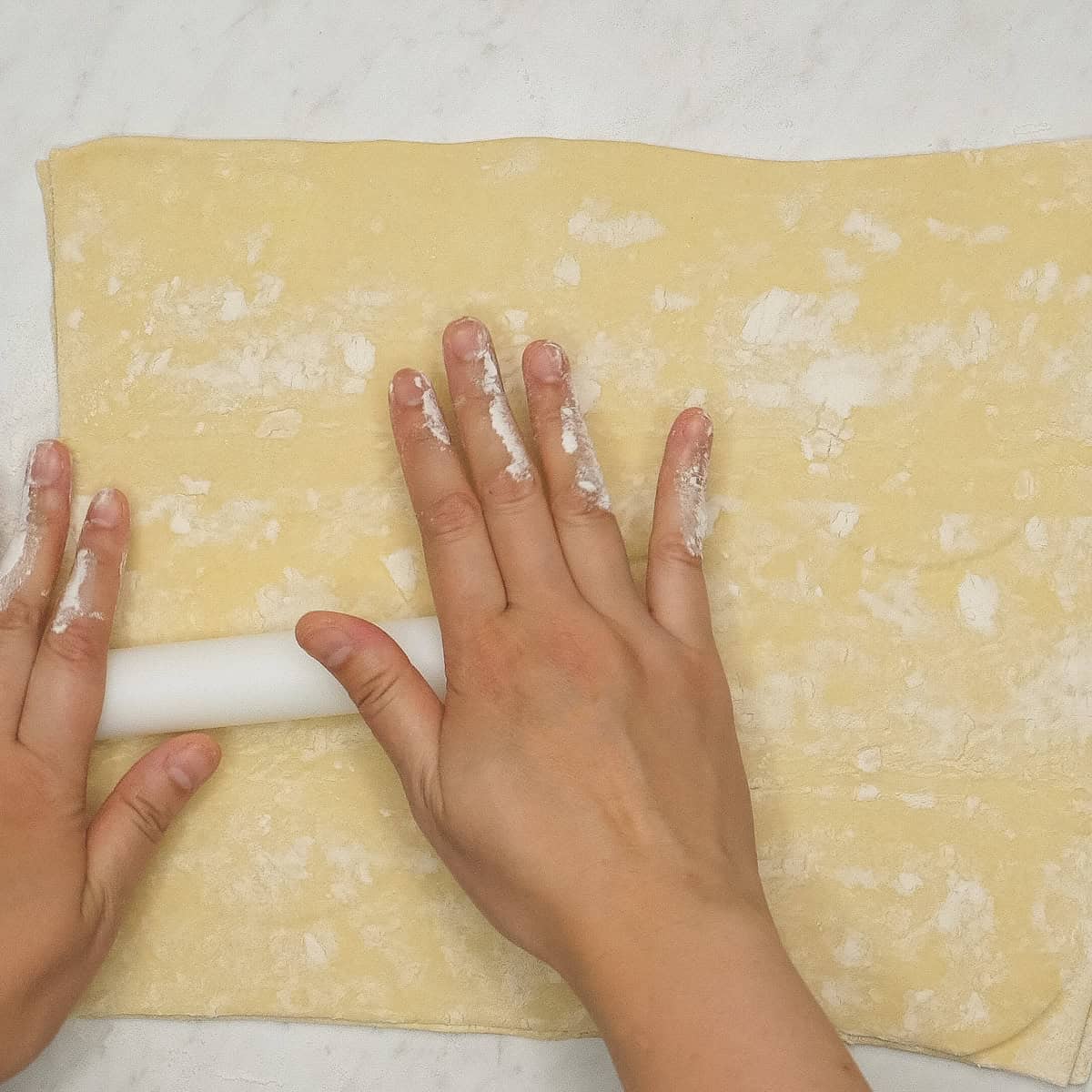 Rolling out the dough using a rolling pin.