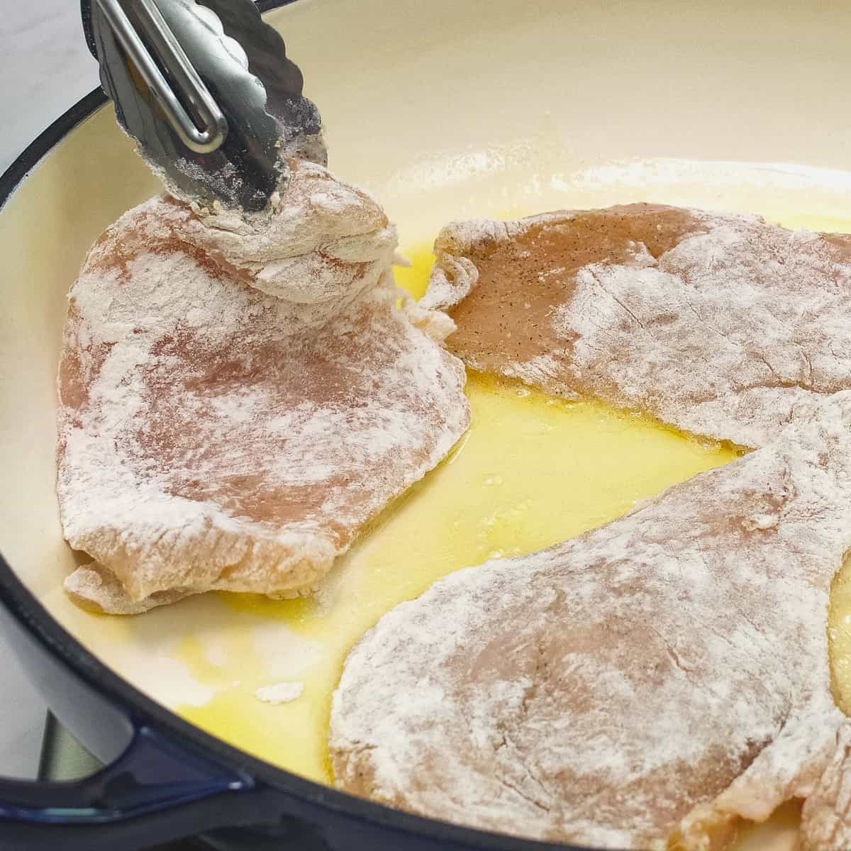 Searing the coated chicken in some oil.