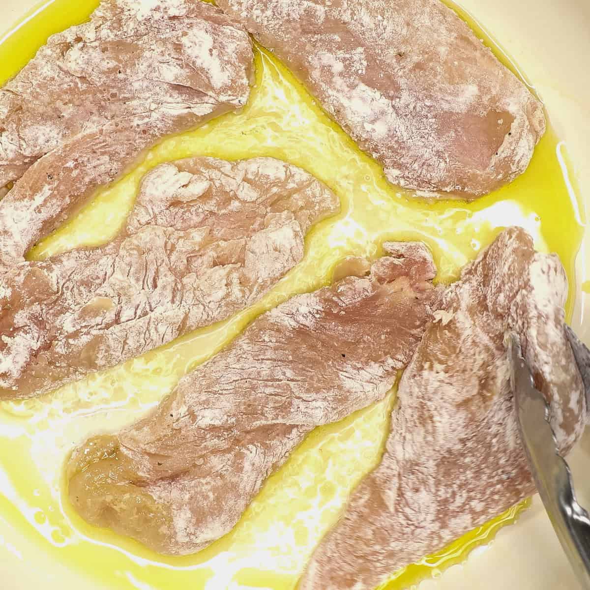 Searing the chicken cutlets in the pan.