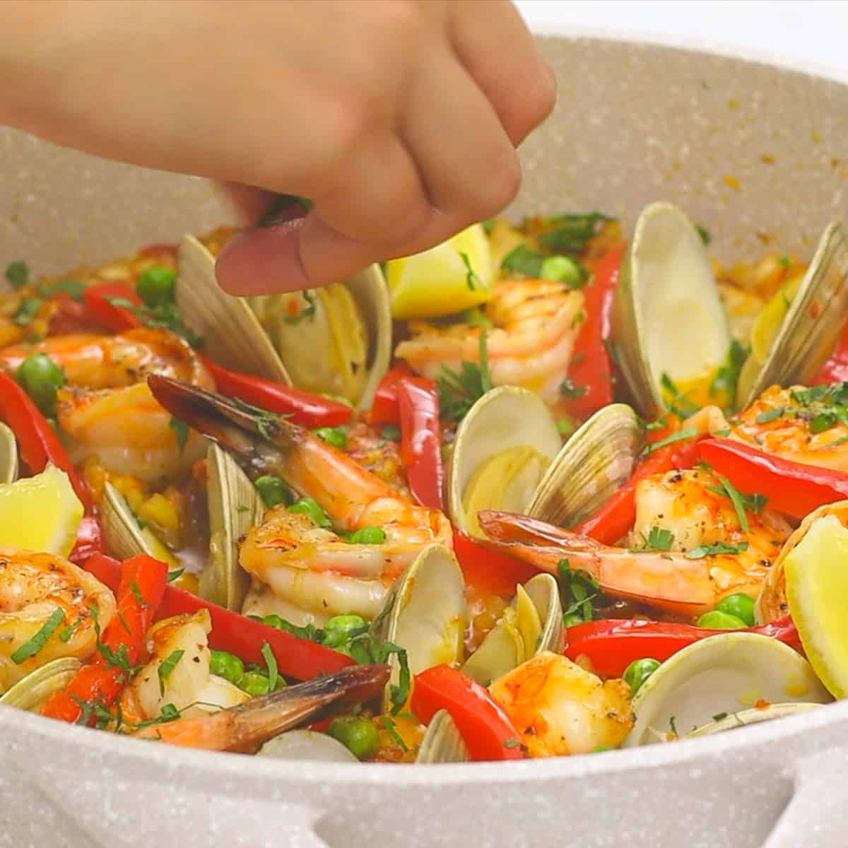 Adding fresh parsley to the Paella in the pan.