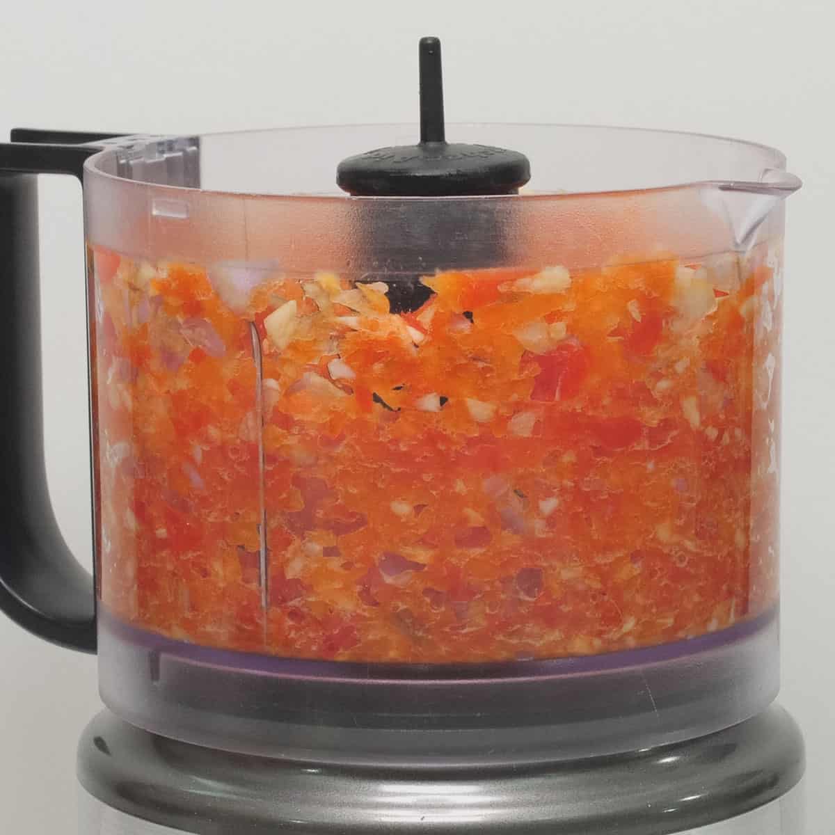 Garlic, shallot, and red bell peppers chopped in a food processor.