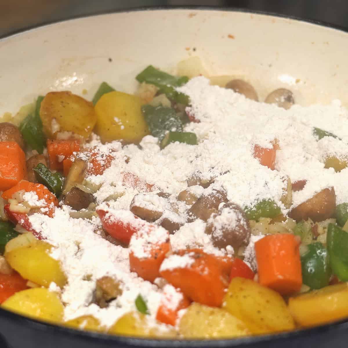Added flour to the sauteed vegetables in the pan.
