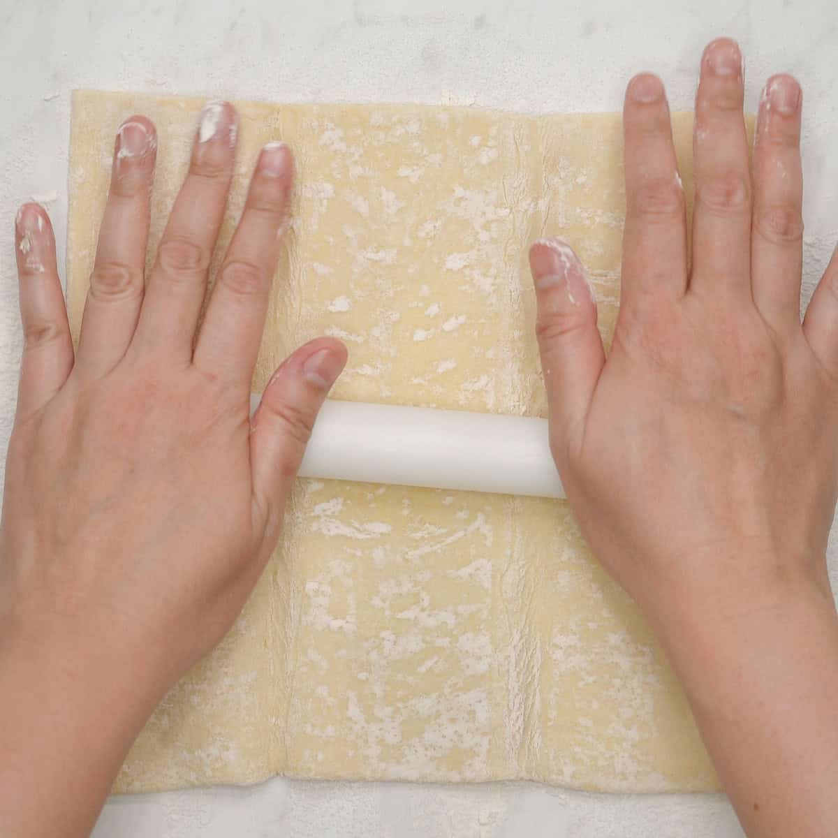Rolling out the puff pastry with a rolling pin.