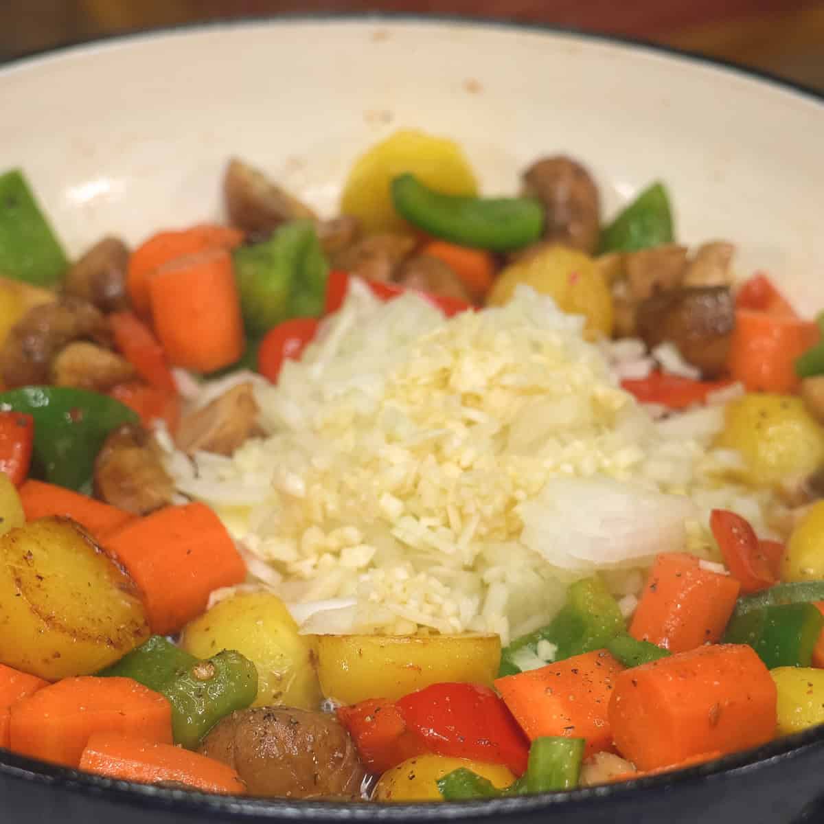 Sauteing onion and garlic with vegetables in a saute pan.