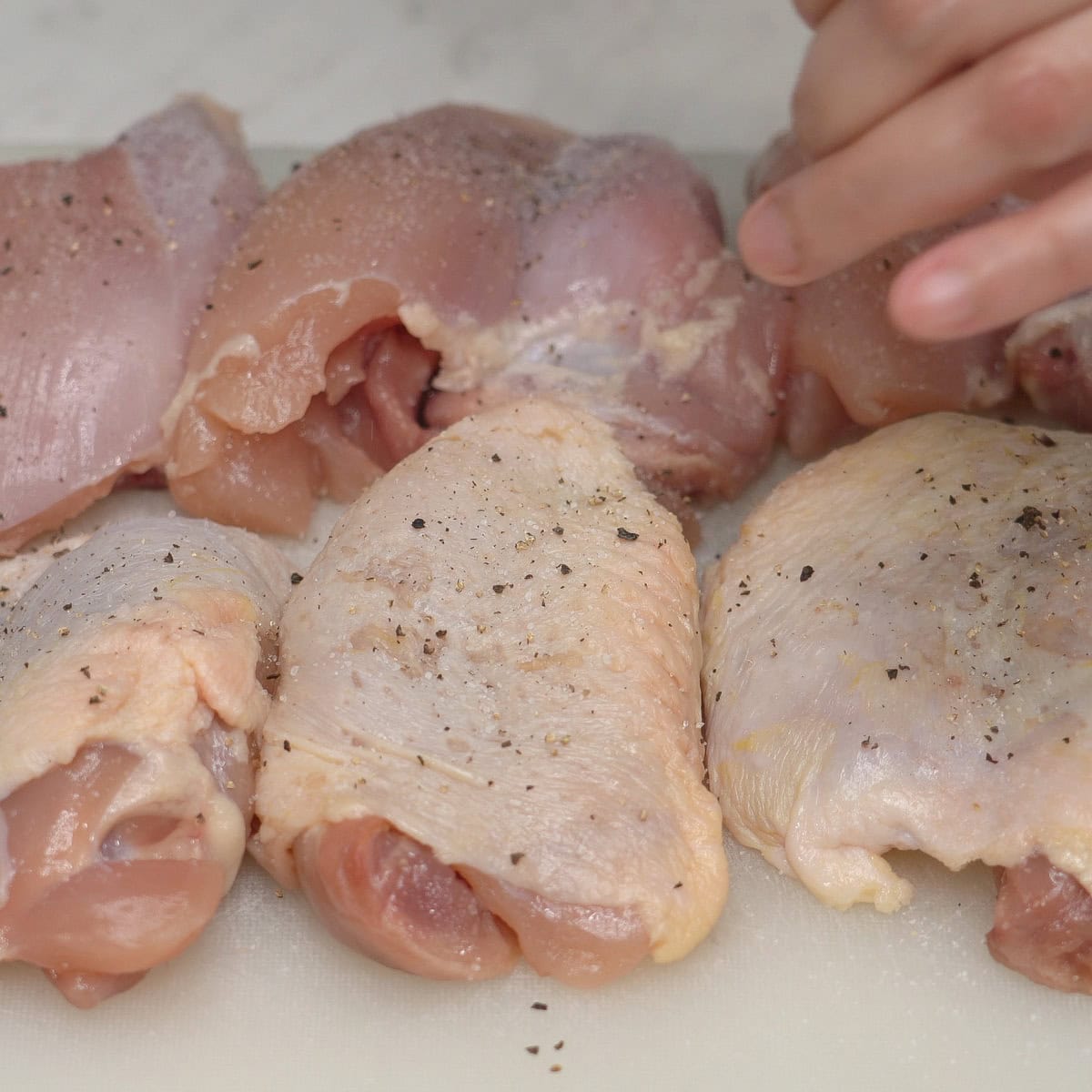 Seasoning chicken thighs with salt and pepper.