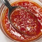 Sweet chili sauce in a bowl scooped by a spoon.