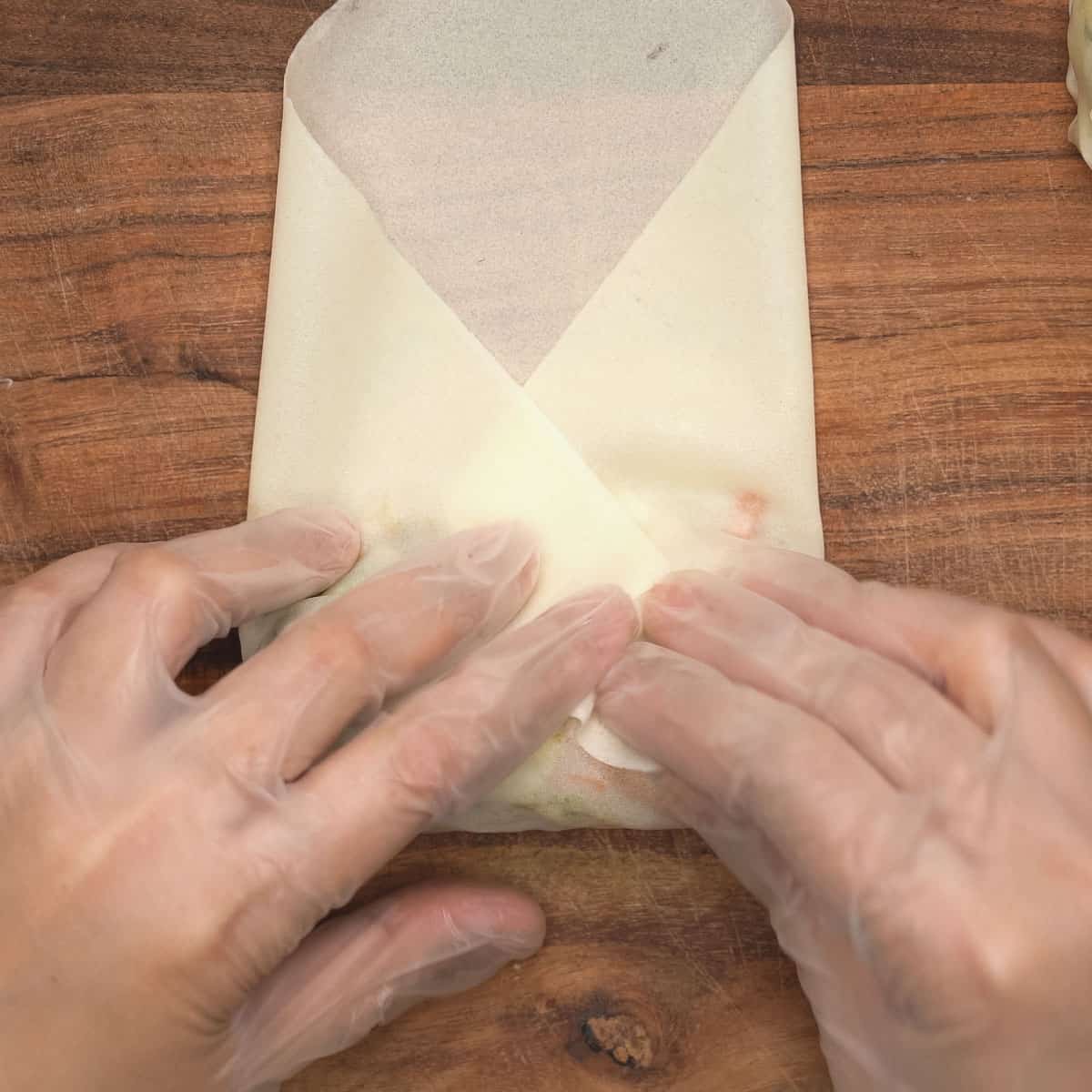 Rolling the lumpia wrapper filled with the vegetable filling.