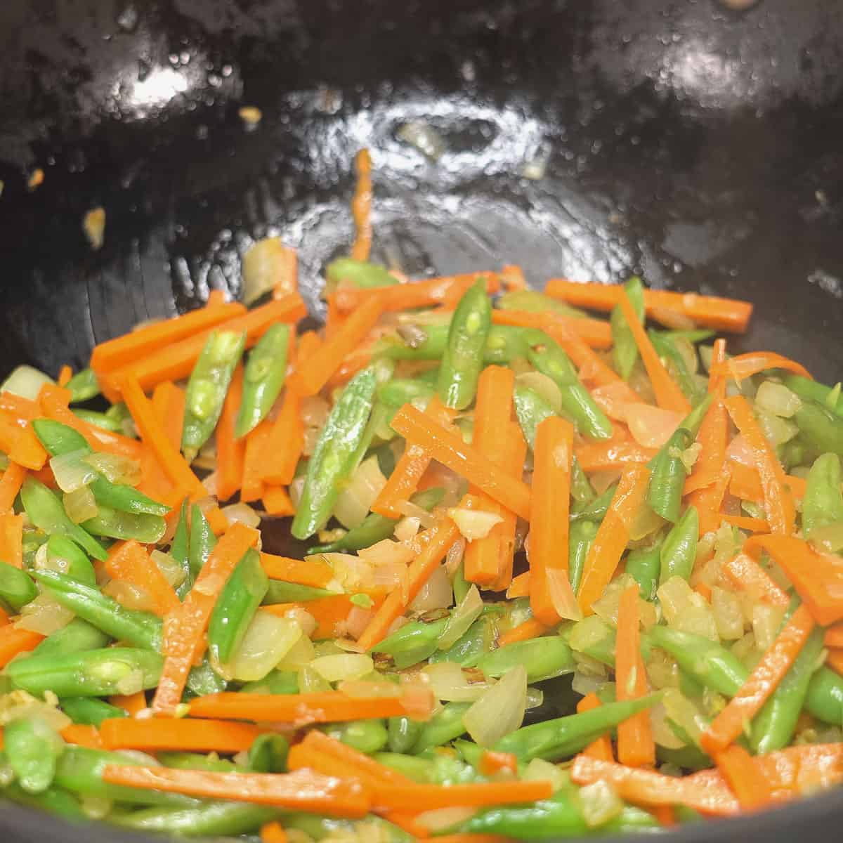 Sauteing the carrots and green beans in a wok.