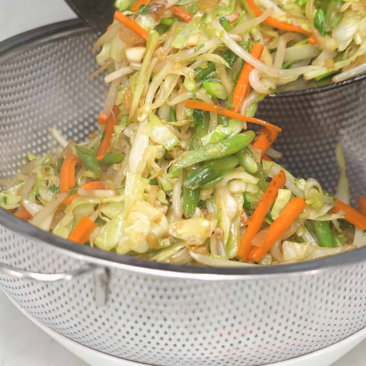 Straining the vegetables over a bowl.